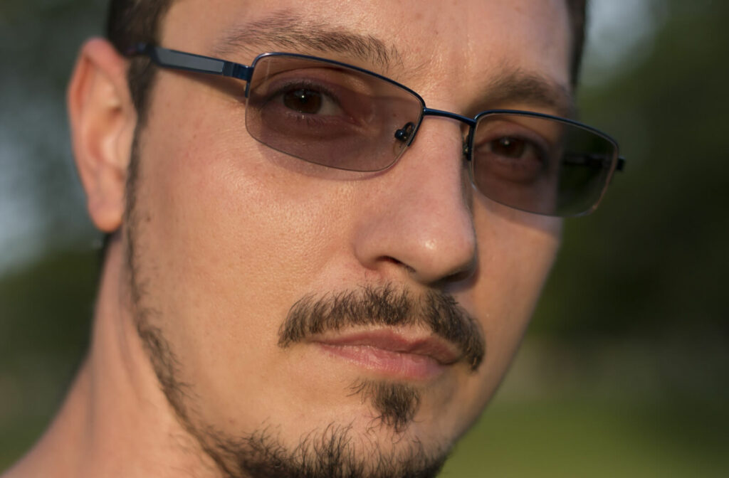 A man wearing eyeglasses with photo-sensitive lenses that auto-darken when comes into contact with UV light.