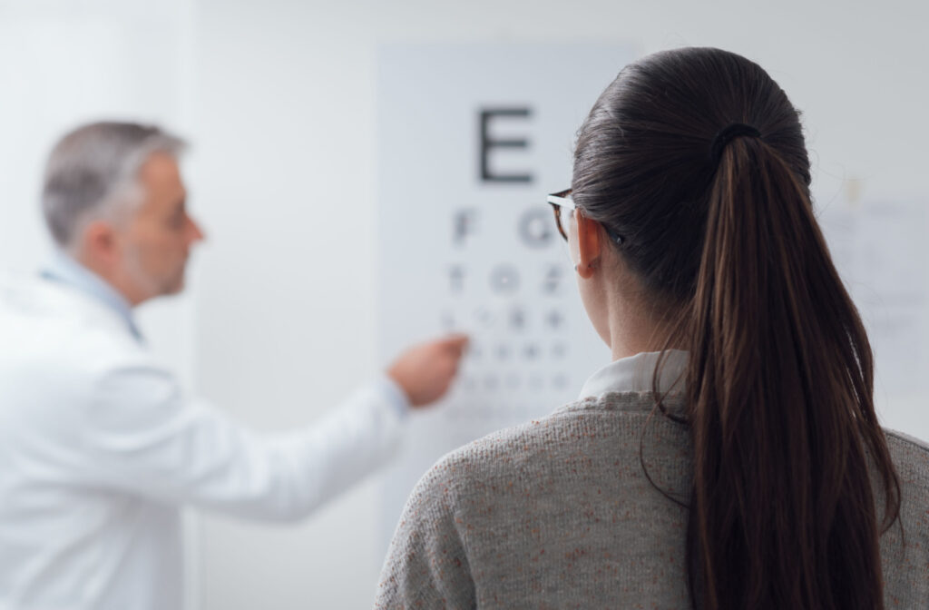 View from behind a patient's head as she sits in a chair and looks at a Snellen chart as directed by the optometrist